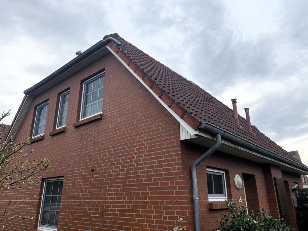 uma casa de tijolos vermelhos com um telhado inclinado em Semi-detached house, Nessmersiel em Neßmersiel