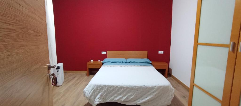 Cama en habitación con pared roja en Habitacions Cal Gueles, en Sanahuja