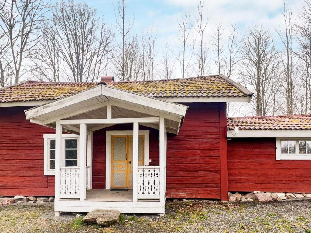 une maison rouge avec un porche blanc et une porte jaune dans l'établissement 5 person holiday home in ÅSEDA, à Åseda