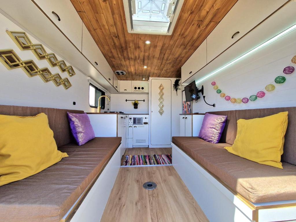 a living room with two couches with yellow and purple pillows at Camper estatico solo para alojar en el frente del Mar in La Tejita