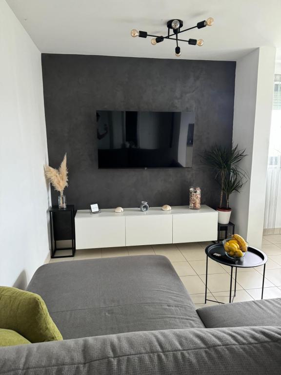 a living room with a couch and a tv on a wall at Apartment Mare in Cunski