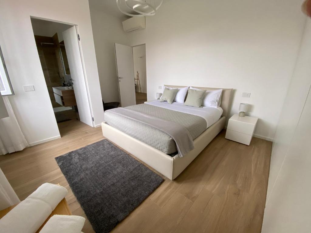 a white bedroom with a large bed and a rug at La casa di GABRIELLA in Milan