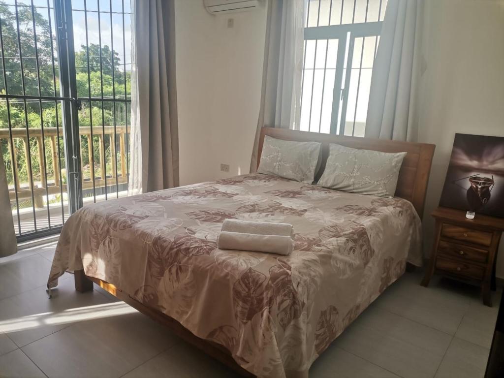 Una cama en un dormitorio con una ventana grande. en VILLA TROU AUX BICHES, en Trou aux Biches