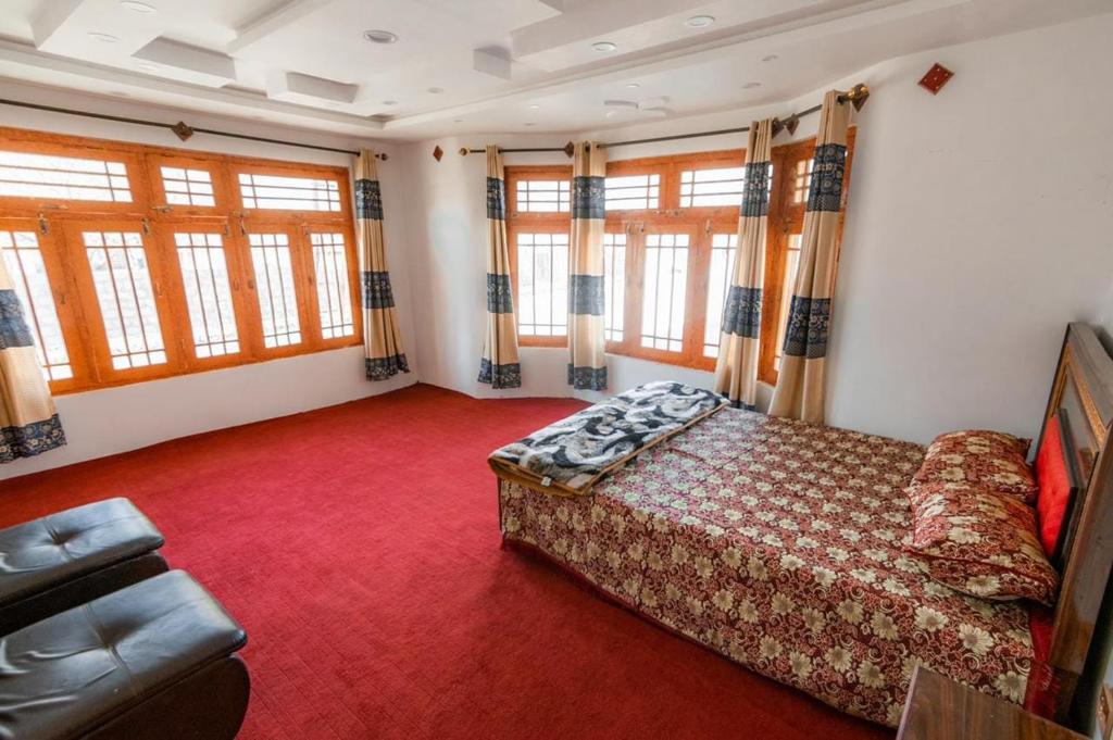 Royal Brangsa Guest House في سكردو: غرفة نوم بسرير واريكة ونوافذ