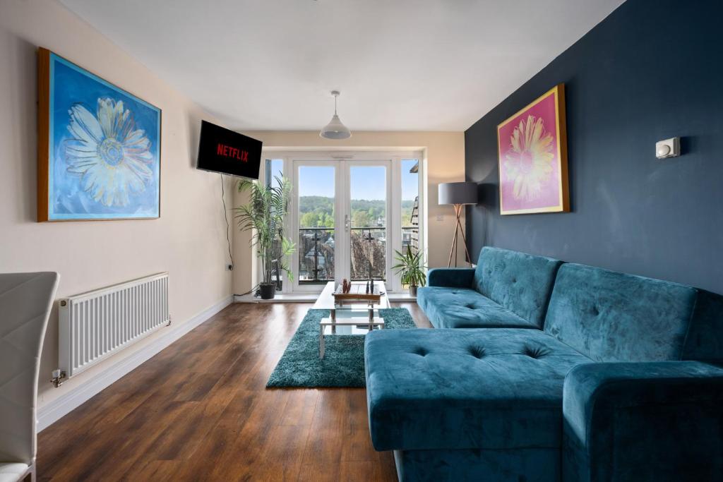 een woonkamer met een blauwe bank en een raam bij High Wycombe Short Stay Apartment in High Wycombe
