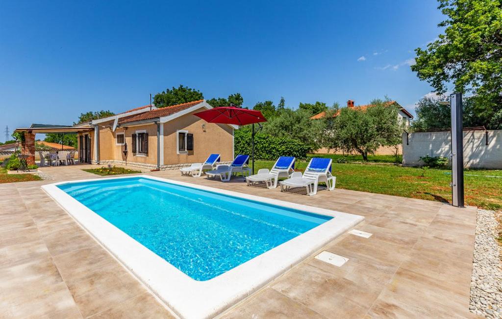 einen Pool in einem Garten mit Stühlen und einem Sonnenschirm in der Unterkunft Kuća Za Odmor Natalie in Medulin