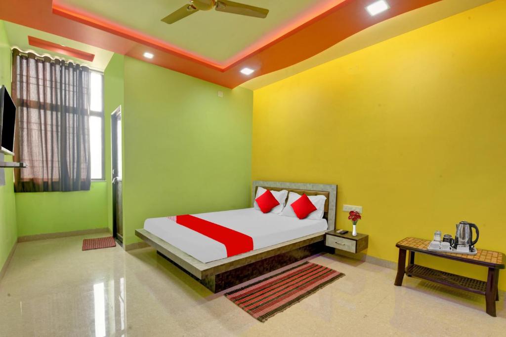 ein Schlafzimmer mit grünen und gelben Wänden und einem Bett mit roten Kissen in der Unterkunft Flagship The Heart Residency in Rāmgarh