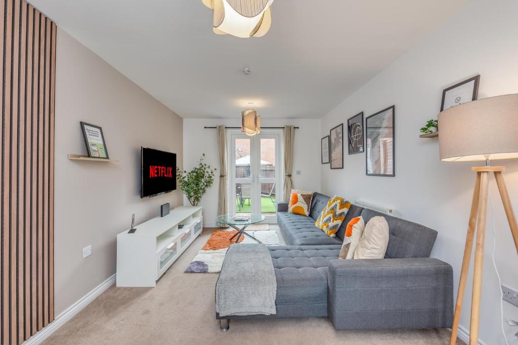 a living room with a couch and a tv at Oakbridge House - 6 mins drive to CMK - Free Parking, Fast WiFi, Smart TVs with Sky and Netflix by Yoko Property in Milton Keynes