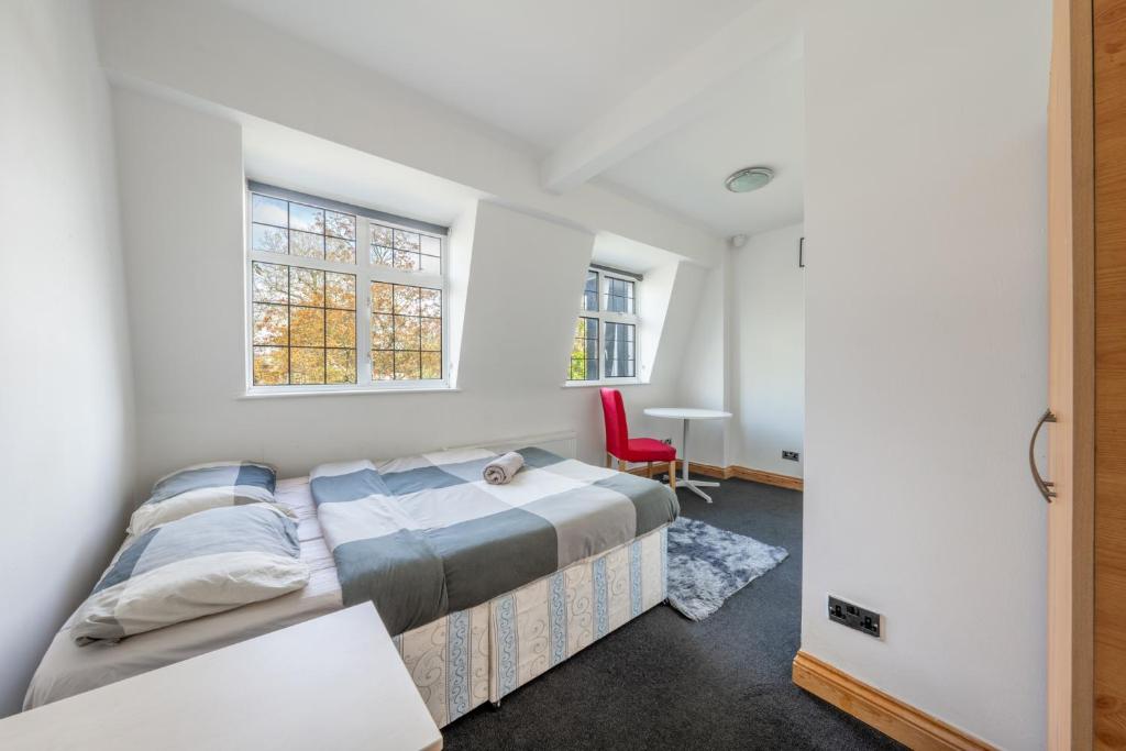a bedroom with a bed and a red chair at Barnet Serviced Accommodation - Elegant 5-Bedroom Home, Just a 7-Minute Stroll from High Barnet Station - Book Your Stay Today!" in New Barnet