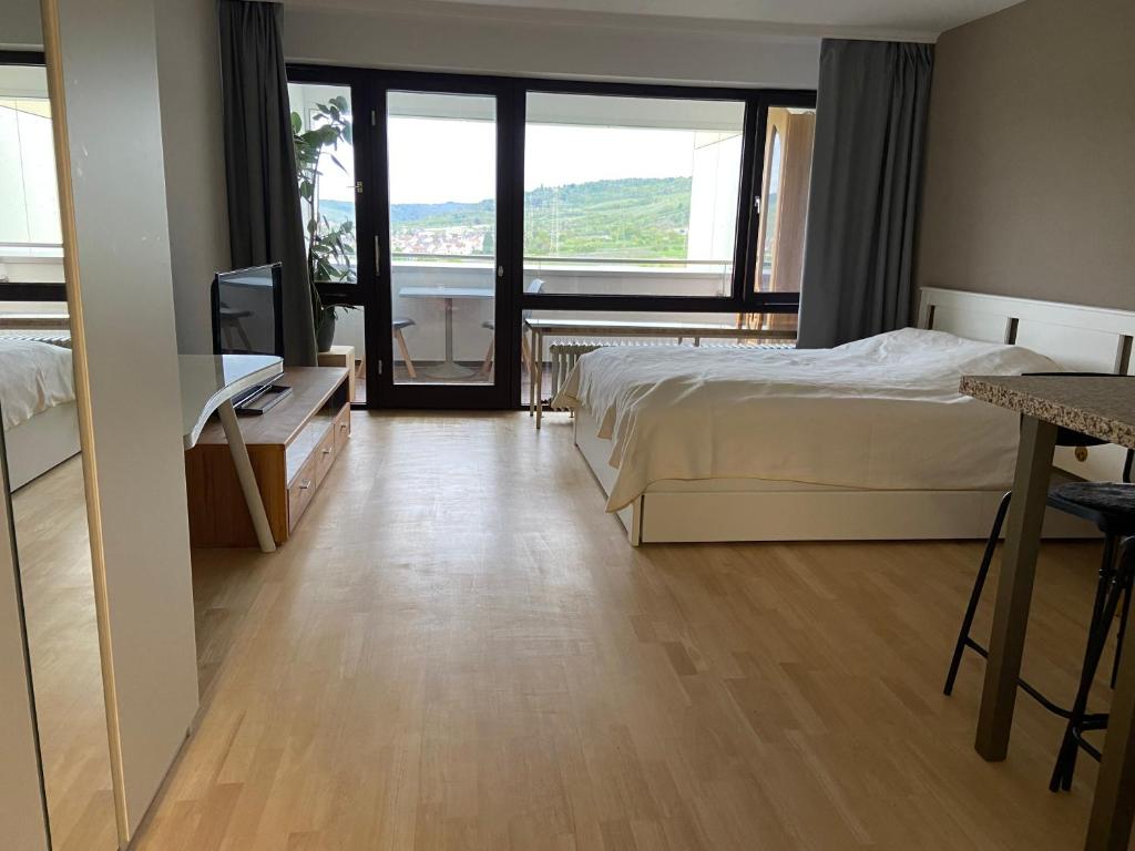 a bedroom with a bed and a television and a balcony at Freshly renovated Studio apartment - top location in Weinstadt in Weinstadt