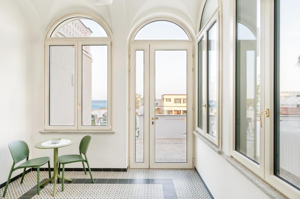Pokój z oknami, stołem i krzesłami w obiekcie Fiko Suite w mieście Roccella Ionica
