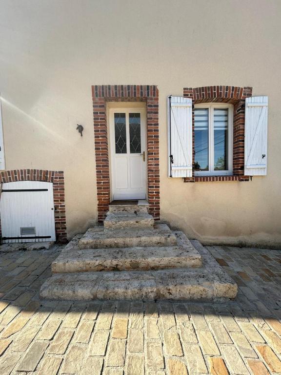 a brick building with stairs leading to a white door at Charmante Maison proche Chartres in Lèves