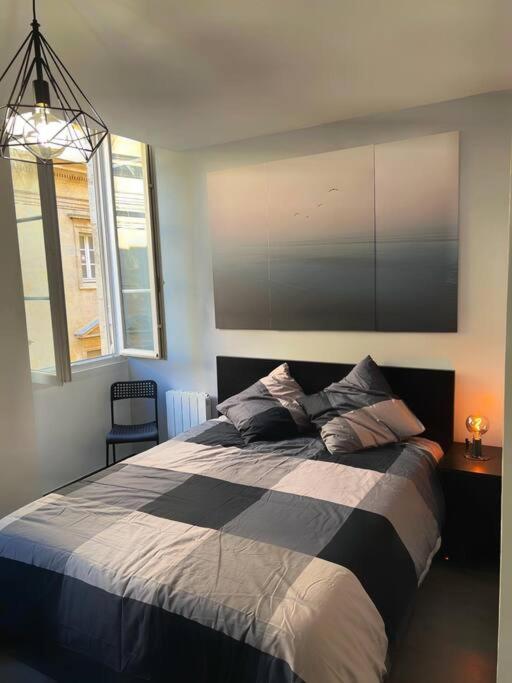 une chambre avec un lit avec une couverture noire et blanche dans l'établissement La Perle Citadine, à Bordeaux