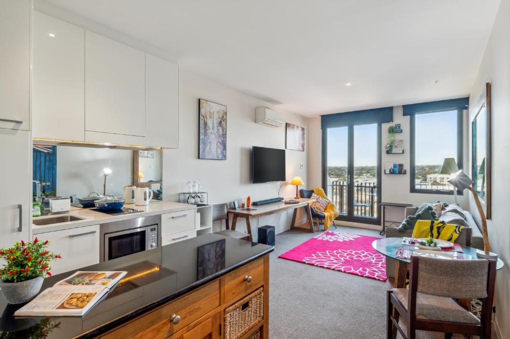 a kitchen with white cabinets and a living room at Seaside Studio Apartment in Frankston, Melbourne in Frankston