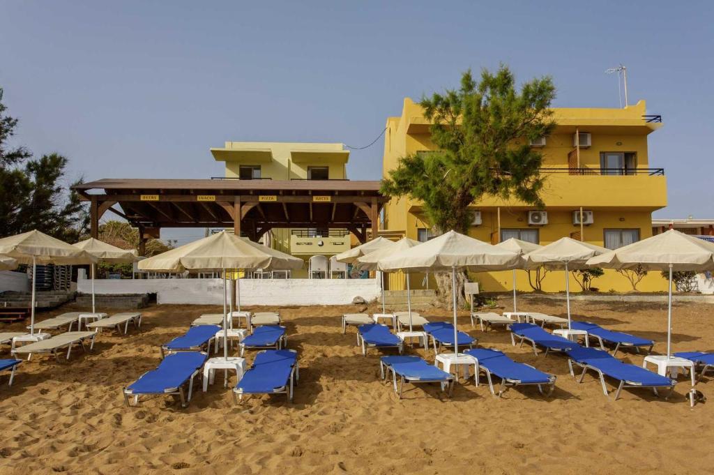 a group of chairs and umbrellas on a beach at Faros Vetoula Suites in Stalos