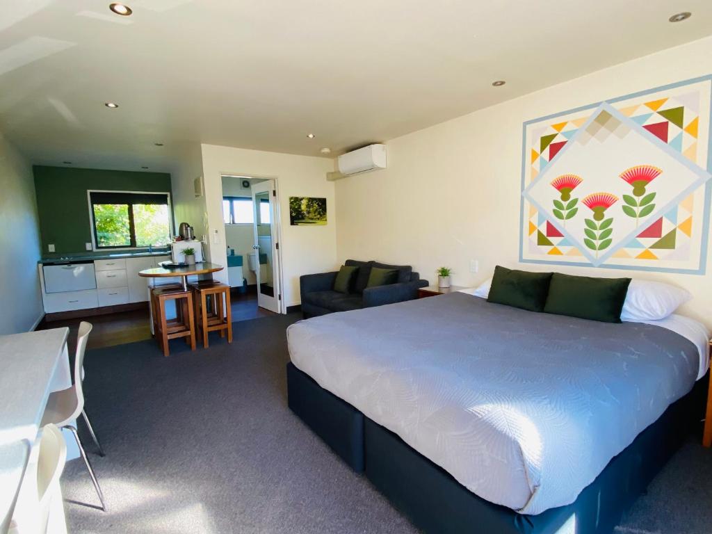 a bedroom with a large bed and a living room at Commodore Motel in Dunedin