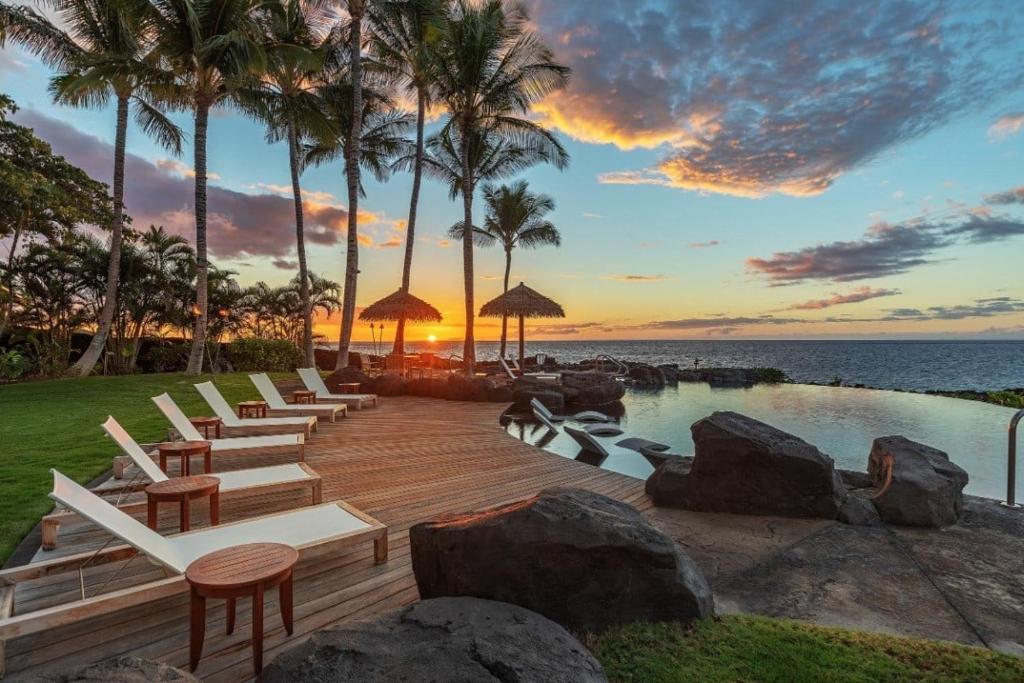 a row of chairs and a swimming pool at a resort at ONE OCEAN OHANA Expansive Views Exclusive Oceanfront Grotto pool plus private pool spa in Waikoloa