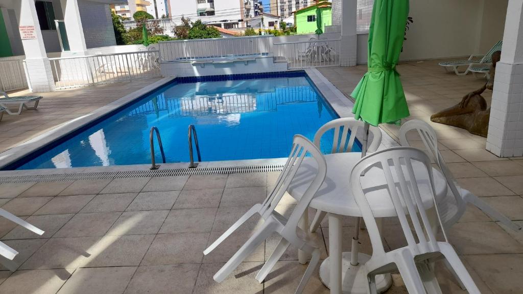 a pool with a table and chairs and an umbrella at Apartamento com piscina Braga Cabo Frio in Cabo Frio