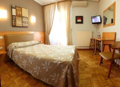 a bedroom with a bed and a table and a television at Hostal Arotza in Tafalla
