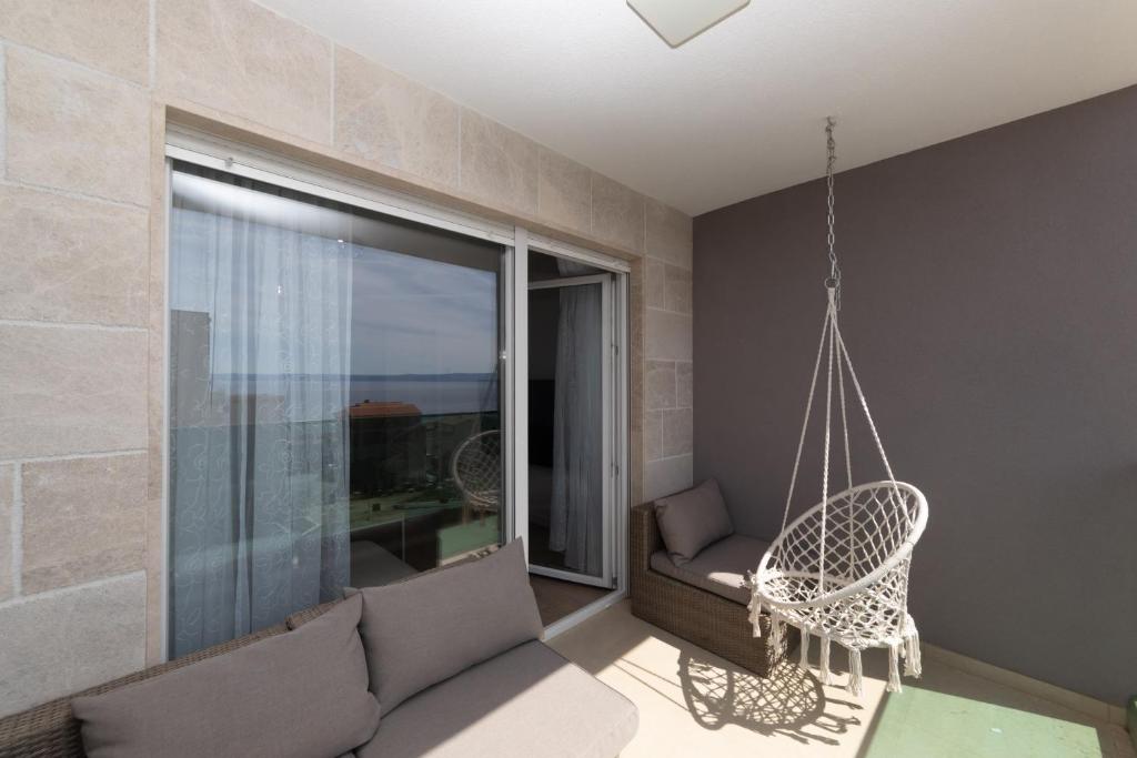 a swinging chair in a room with a large window at Luxury Apartments Sunny Side in Makarska