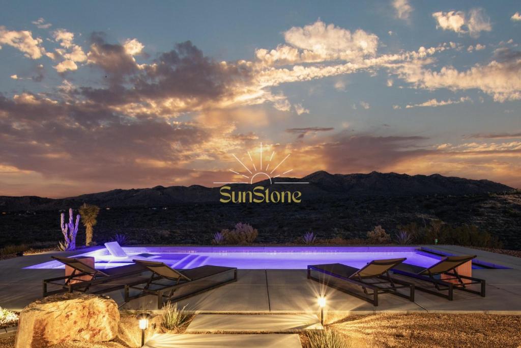 een patio met stoelen en een zonnebord bij zonsondergang bij Sunstone Pool, Hot Tub & Mountain Views! in Yucca Valley