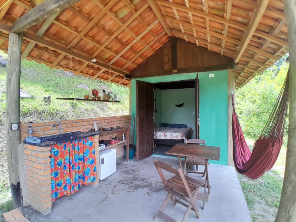 una habitación con una mesa y una hamaca en una casa en Chalé Floresta Toca da Serra, en Iporanga