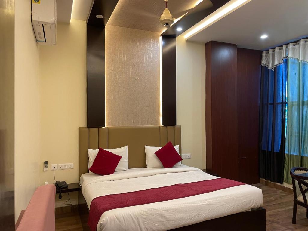 1 dormitorio con 1 cama grande con almohadas rojas en Hotel City Star Family Stay en Mathura