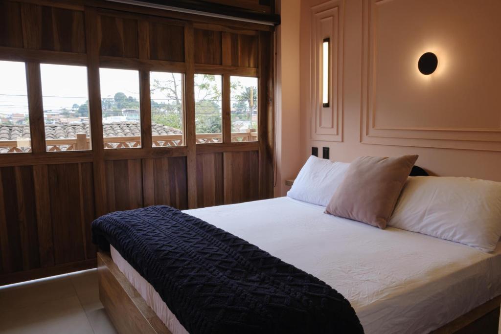 a bedroom with a bed with white sheets and windows at BINDI in Salento