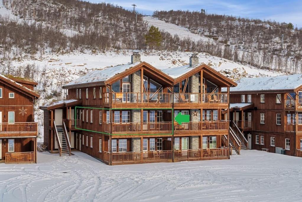 een groot houten gebouw in de sneeuw voor een berg bij Cozy Apartment close to Hovden alpine centre in Hovden