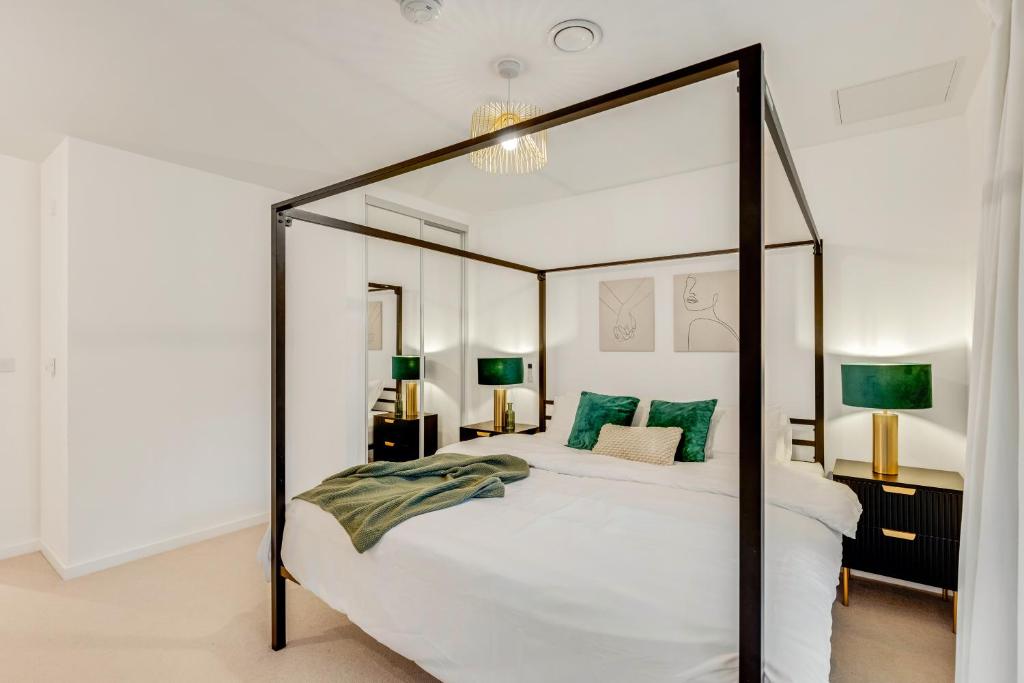 ein Schlafzimmer mit einem großen weißen Bett mit grünen Kissen in der Unterkunft Khayat Homes - The Emerald - Two Bed Luxury Apt in North Woolwich