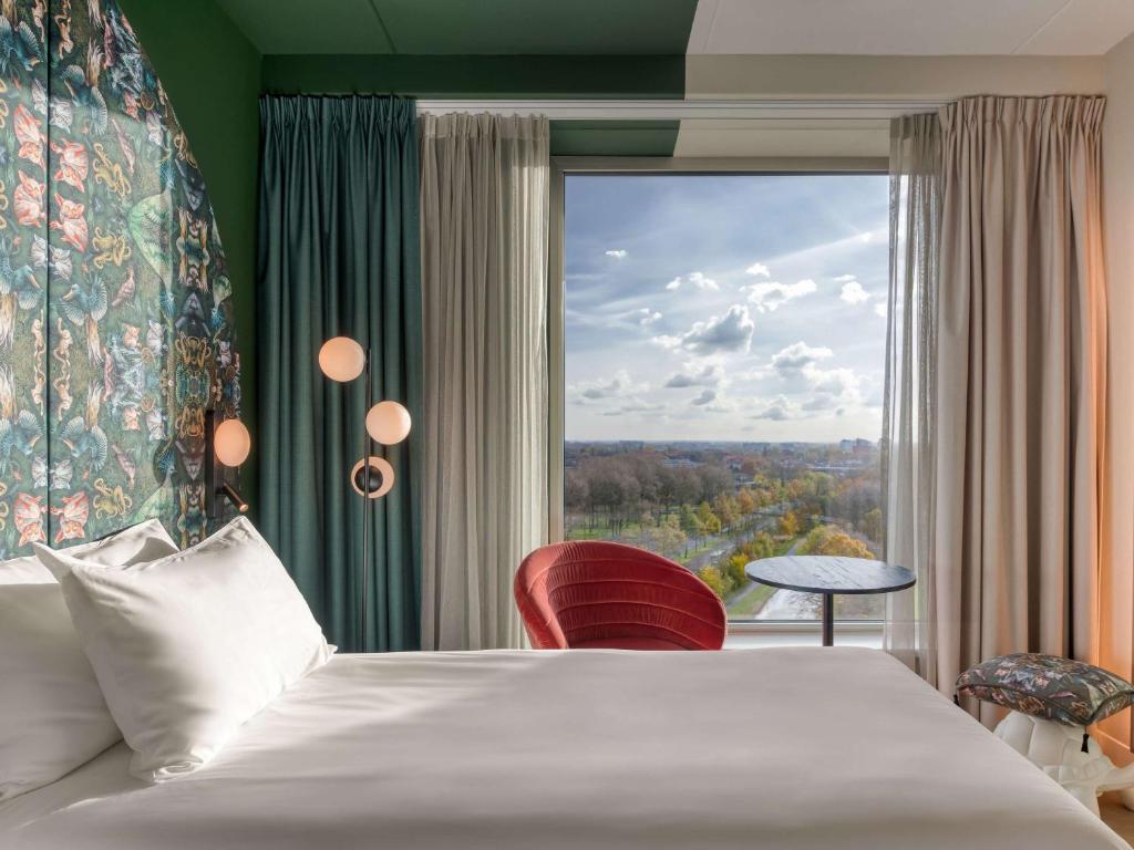 una camera d'albergo con un letto e una grande finestra di ibis Styles Rotterdam Ahoy a Rotterdam