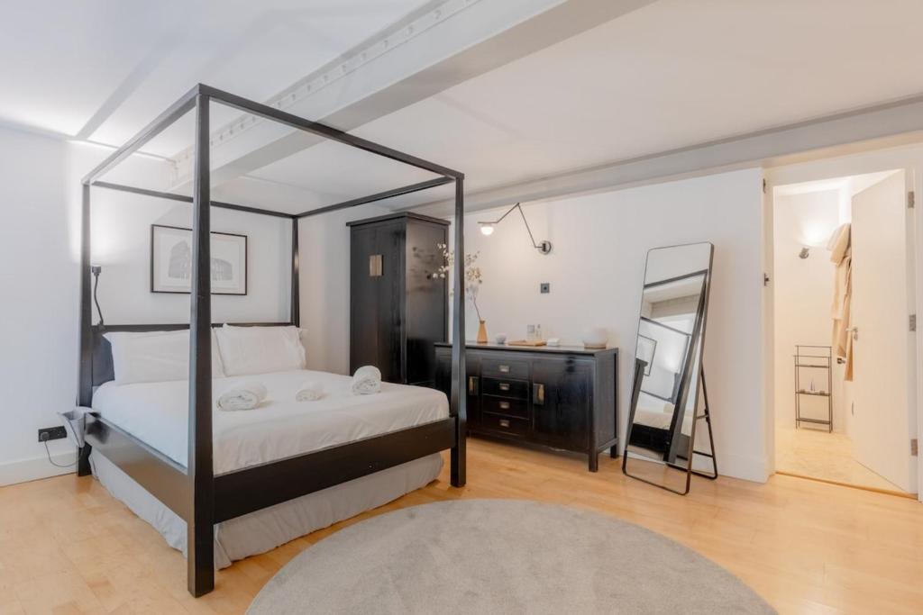 a bedroom with a four poster bed and a mirror at Chic 1BD Maisonette wHot Tub King's Cross! in London