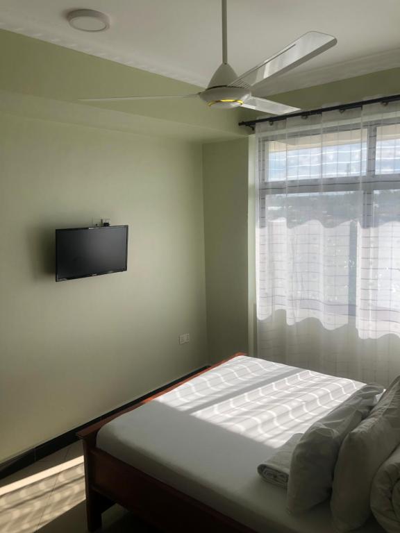 ein Schlafzimmer mit einem Bett und einem TV an der Wand in der Unterkunft Mbazi Hotel in Tanga