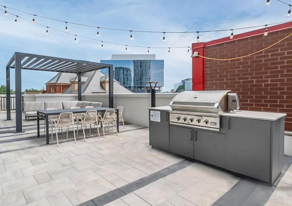 a patio with a grill and a table and chairs at Stylish 2BR Condo - Balcony - Stunning City View in Kitchener