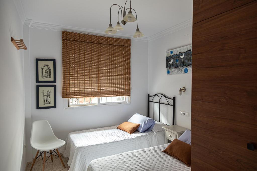巴亞納的住宿－Apartamento San Miguel，一间卧室设有两张床、一把椅子和一个窗户。