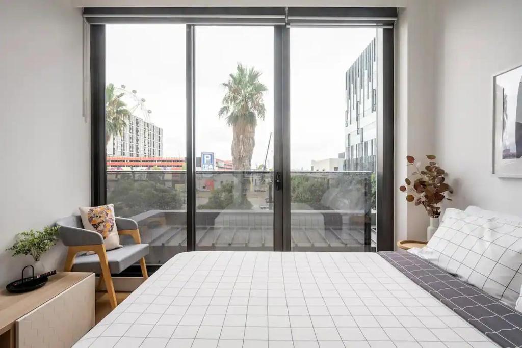 a bedroom with a white bed and a large window at Centrally Located Modern Loft w Free Parking, Infinity Pool, Workspace in Melbourne