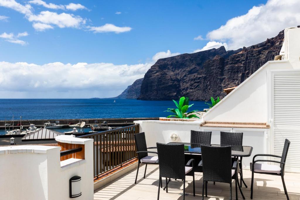 a balcony with a table and chairs overlooking the ocean at OCEAN PANORAMA - 3 AC bedrooms, private garage, pool, 2 bathrooms, tv channels in Acantilado de los Gigantes