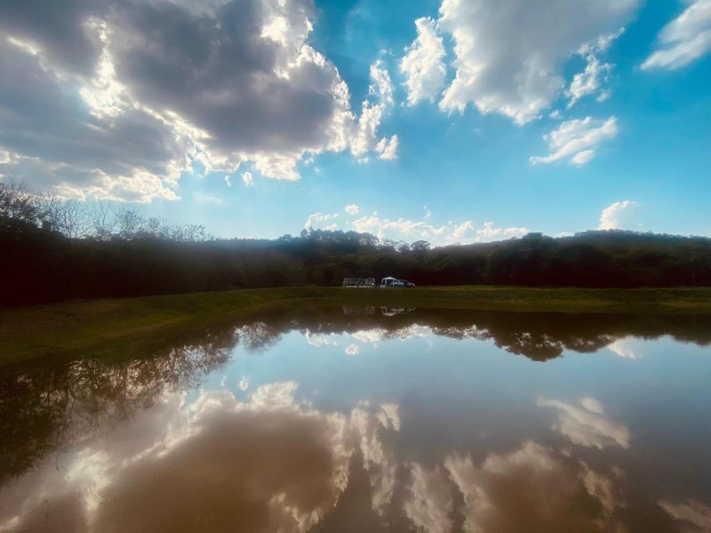 a reflection of the sky and clouds in a pond at Vila Eco Mobili in São Roque