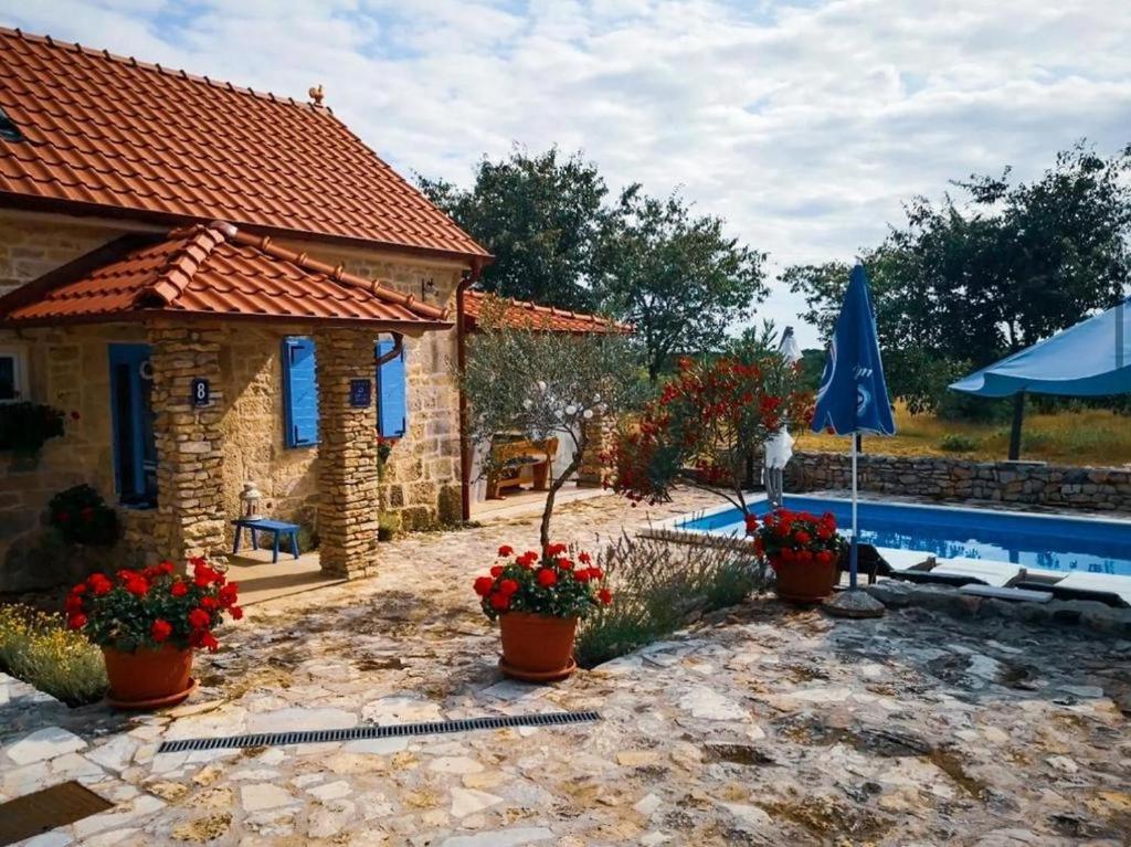 a house with a swimming pool and a blue umbrella at Holiday house with a swimming pool Puljane, Krka - 23038 in Drniš