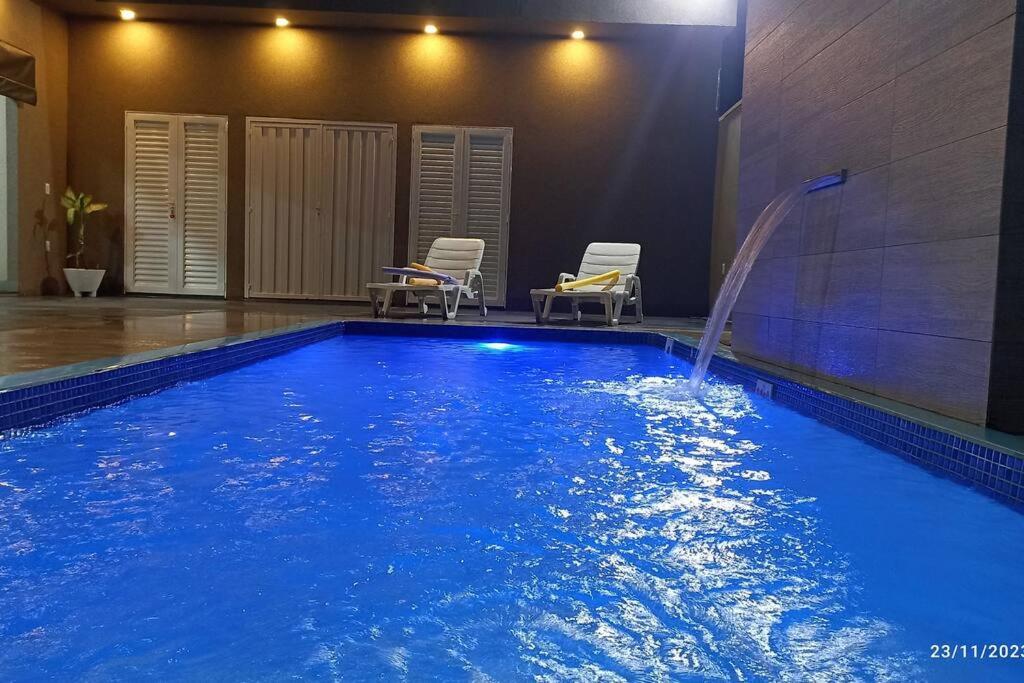 a swimming pool with two chairs and a water fountain at Recanto Matheus Casa de Temporada Olímpia SP in Olímpia