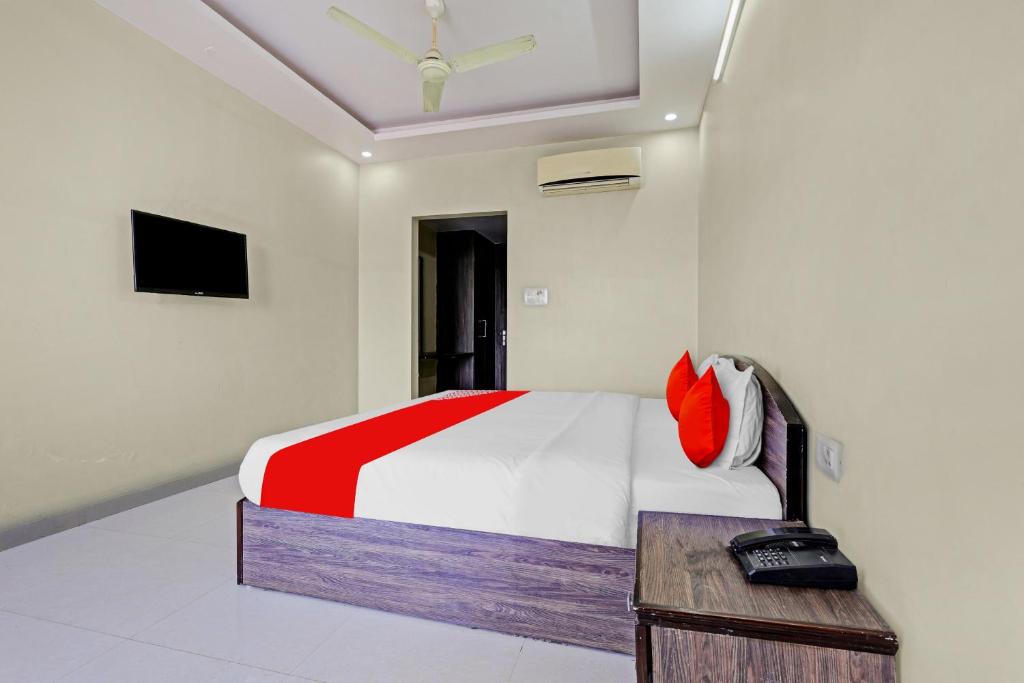 sypialnia z łóżkiem z czerwonymi poduszkami i telefonem w obiekcie SPOT ON 81091 Gmall w mieście Haldwani