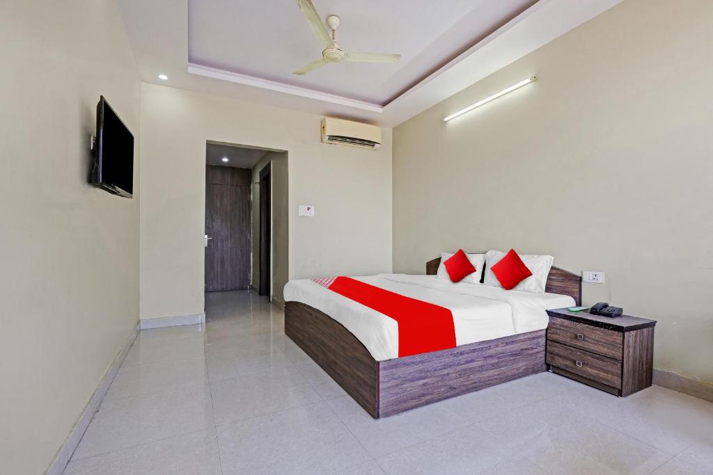 Schlafzimmer mit einem Bett mit roten Kissen und einem TV in der Unterkunft SPOT ON 81091 Gmall in Haldwani-Kathgodam