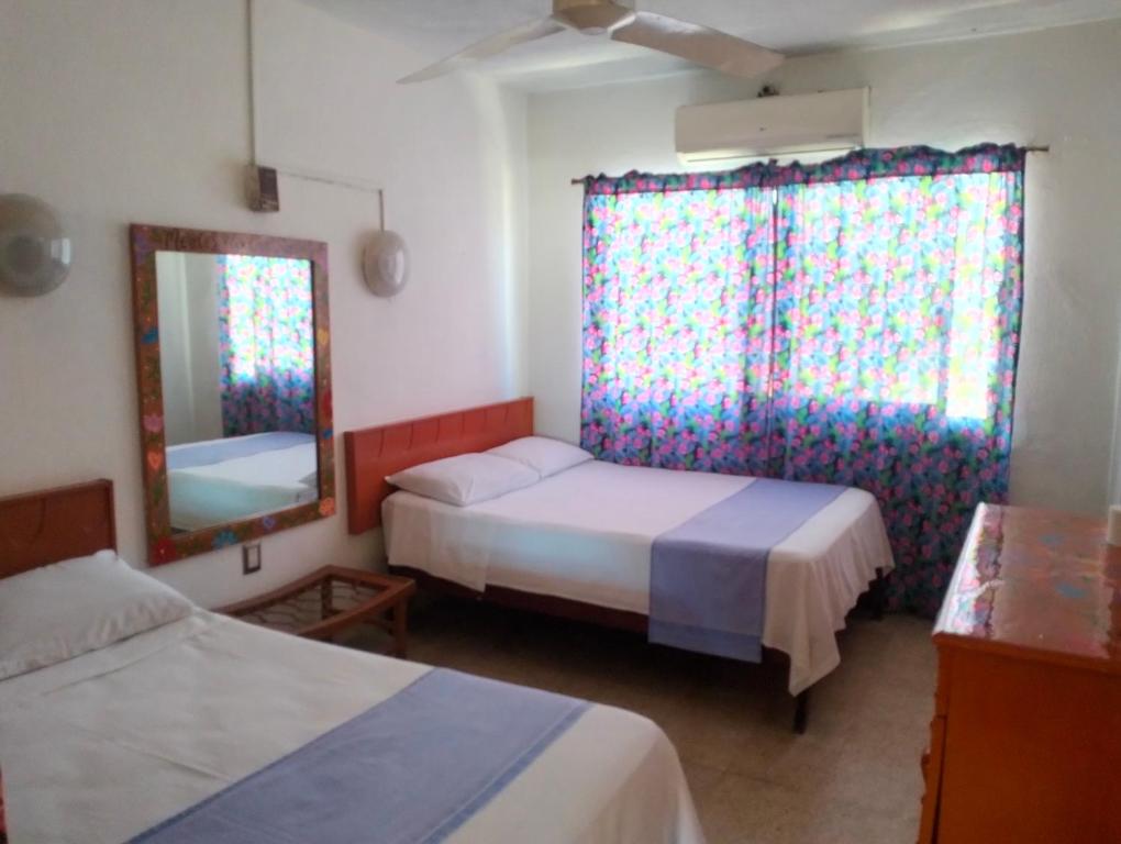a bedroom with two beds and a mirror and a window at Hotel Beatriz in Acapulco
