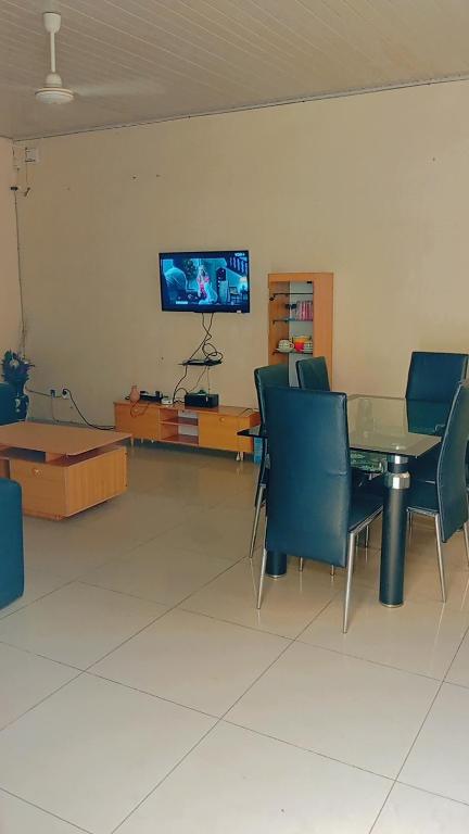 Un comedor con mesa y sillas y un televisor. en Timba coquette-loge, en Cotonou