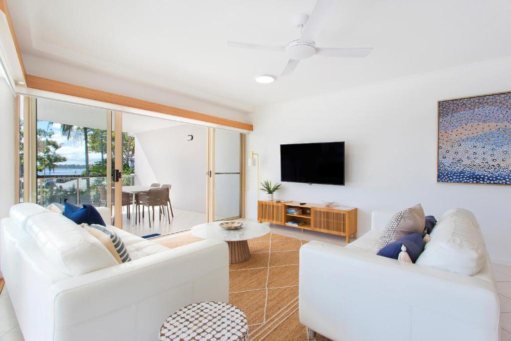 a living room with two white couches and a tv at Offshore Noosa Resort in Noosaville
