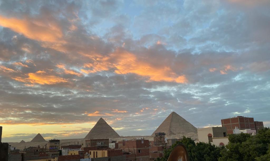 einen Blick auf die Pyramiden einer Stadt bei Sonnenuntergang in der Unterkunft 4 Pyramids inn in Kairo