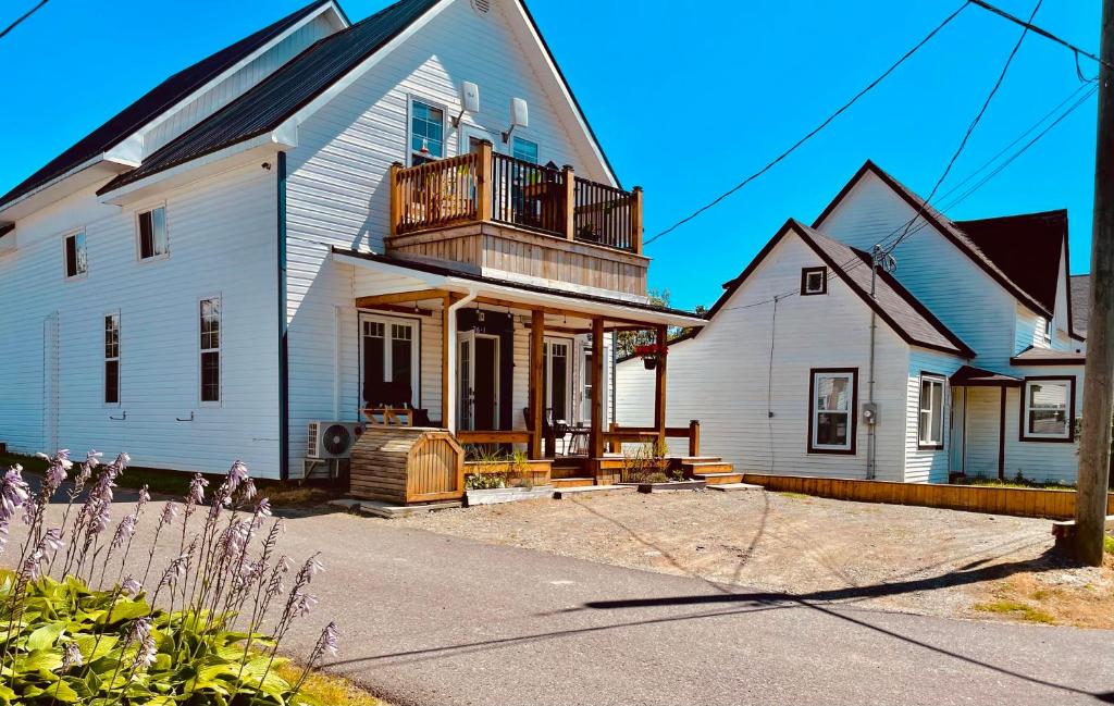 ein großes weißes Haus mit einer Veranda und einem Balkon in der Unterkunft Finn's Studio, Fundy Park in Alma
