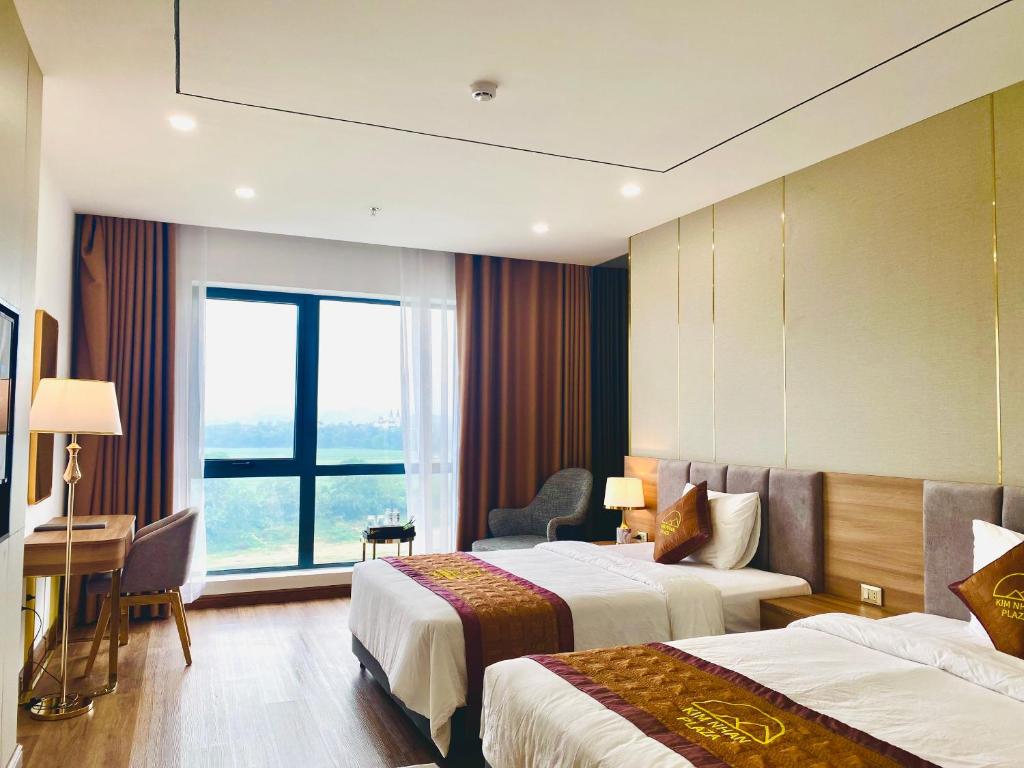 Habitación de hotel con 2 camas y escritorio en KHÁCH SẠN KIM NHAN, en Anh Sơn