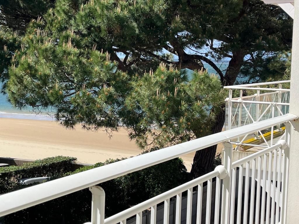 un escalier blanc à côté d'un arbre et de la plage dans l'établissement Jolie T2 à Arcachon - Parking, WiFi, Proche Plage - FR-1-374-3, à Arcachon