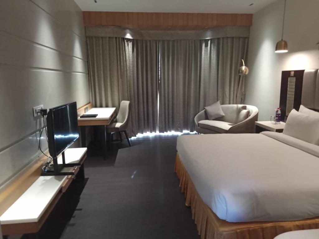 a hotel room with a bed and a desk and a tv at The Red Maple Mashal in Indore